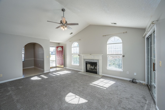 unfurnished living room with a textured ceiling, carpet floors, a fireplace, vaulted ceiling, and ceiling fan