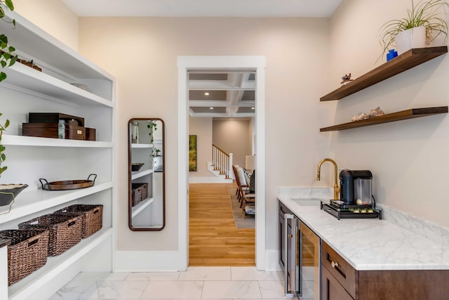 interior space featuring marble finish floor, coffered ceiling, a sink, and open shelves