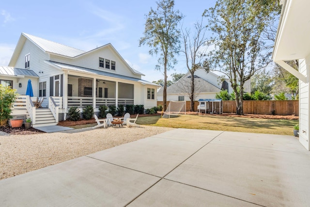 view of front of home featuring a front yard, metal roof, an outdoor fire pit, and a patio