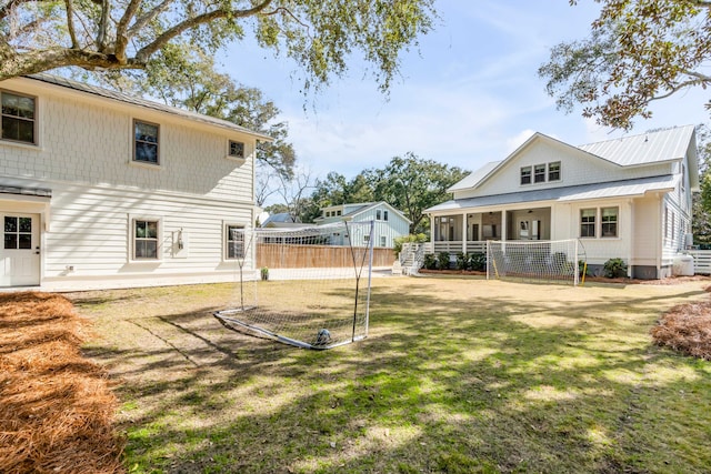 back of property featuring a yard, a standing seam roof, metal roof, and fence