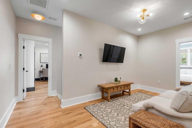 living room featuring light wood-type flooring, baseboards, and visible vents