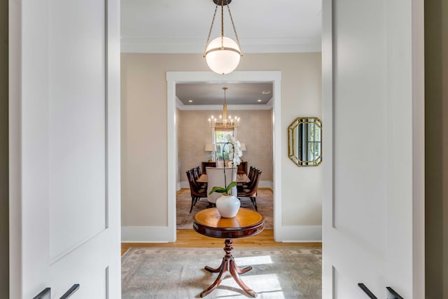 corridor featuring a chandelier, crown molding, baseboards, and wood finished floors