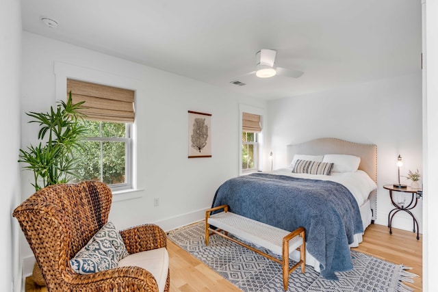 bedroom with ceiling fan, multiple windows, wood finished floors, and visible vents