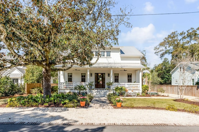 view of front facade with a front yard, covered porch, and fence