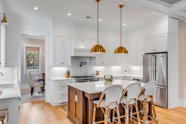 kitchen with visible vents, white cabinets, light wood-style flooring, high quality fridge, and a sink