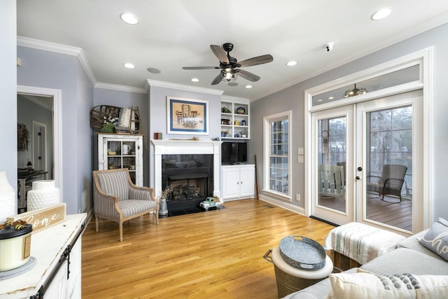 living area with light wood finished floors, recessed lighting, a tile fireplace, and crown molding