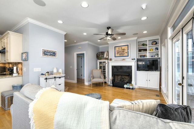 living area with light wood finished floors, baseboards, a fireplace with flush hearth, ornamental molding, and recessed lighting