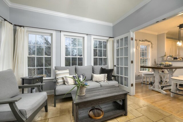 living area featuring crown molding, baseboards, and stone tile flooring