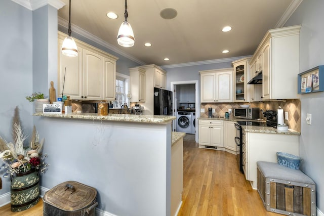 kitchen with range with electric cooktop, stainless steel microwave, tasteful backsplash, a peninsula, and washer / dryer