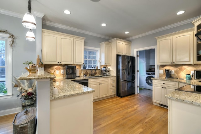 kitchen with black appliances, a sink, washer / clothes dryer, cream cabinets, and a peninsula