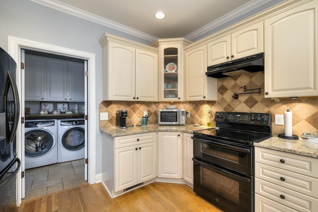 kitchen with under cabinet range hood, cream cabinetry, black appliances, and washing machine and dryer