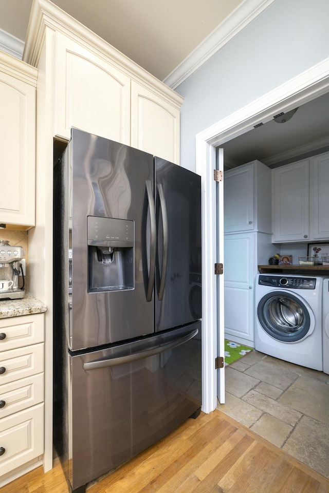 kitchen with light wood-style flooring, ornamental molding, light stone counters, washer / clothes dryer, and black refrigerator with ice dispenser