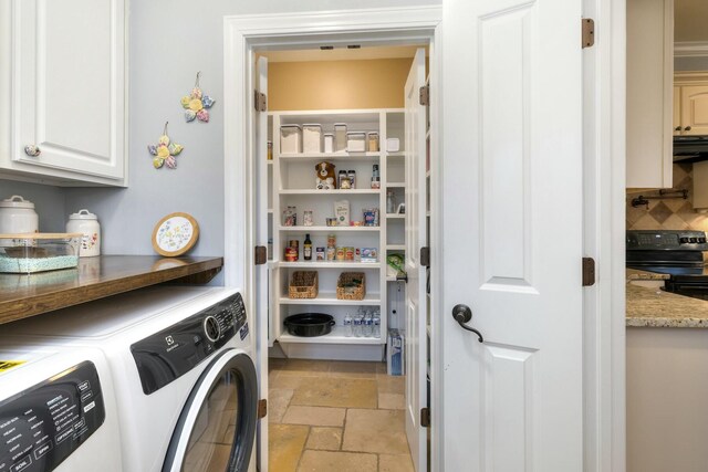 clothes washing area with cabinet space, stone tile floors, and washing machine and dryer