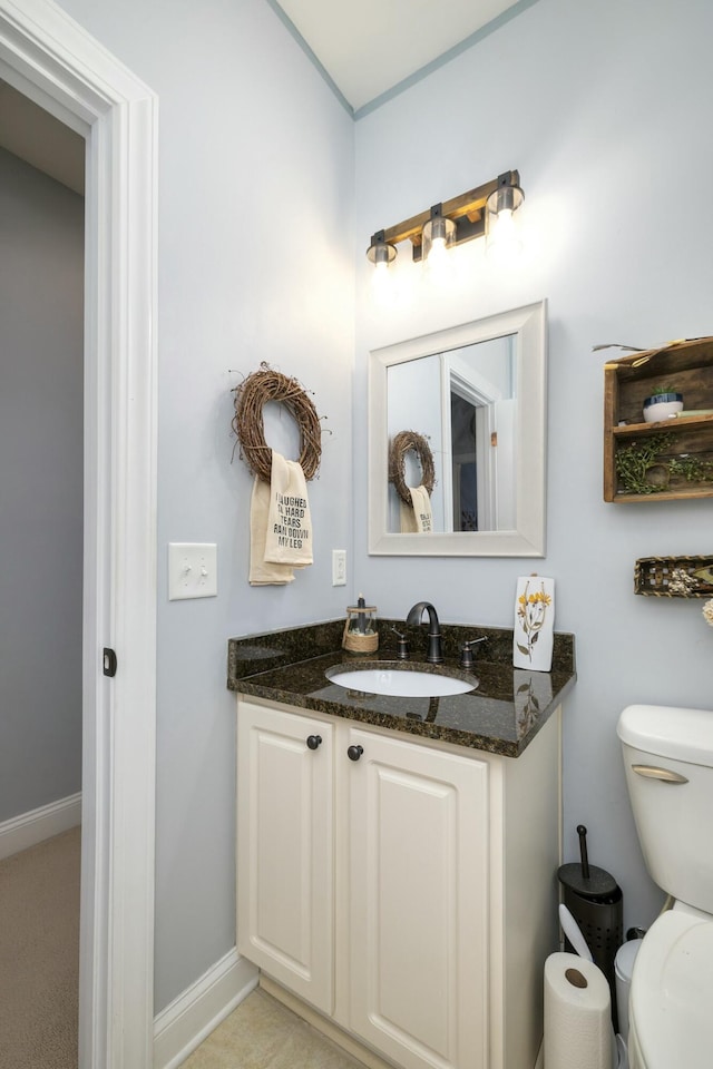 bathroom with toilet, vanity, and baseboards