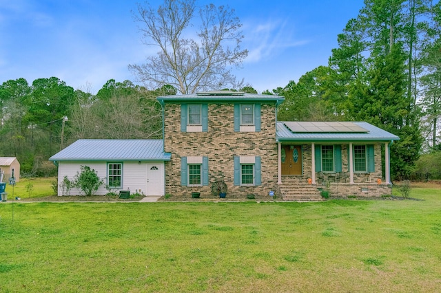 276 S Railroad Ave, Harleyville, SC 29448 - view of front facade with roof mounted solar panels, metal roof, a front lawn, and brick siding