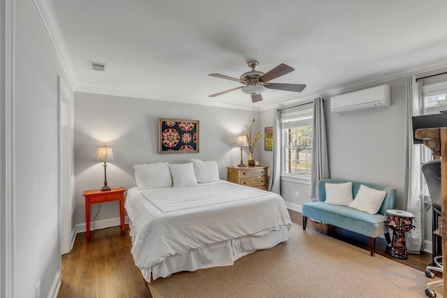 bedroom with wood finished floors, visible vents, baseboards, a wall mounted AC, and crown molding