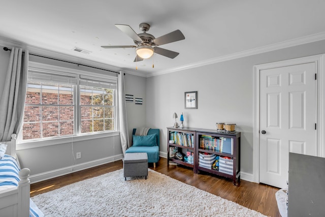 sitting room with crown molding, visible vents, a ceiling fan, wood finished floors, and baseboards