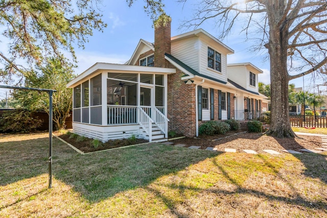 back of property featuring brick siding, fence, a sunroom, a lawn, and a chimney