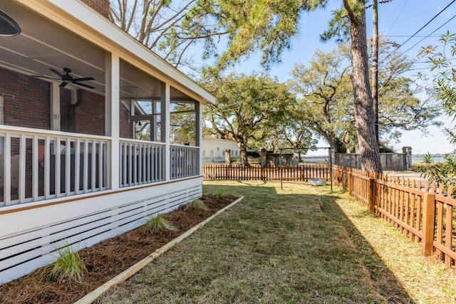 view of yard featuring fence, a sunroom, and a ceiling fan