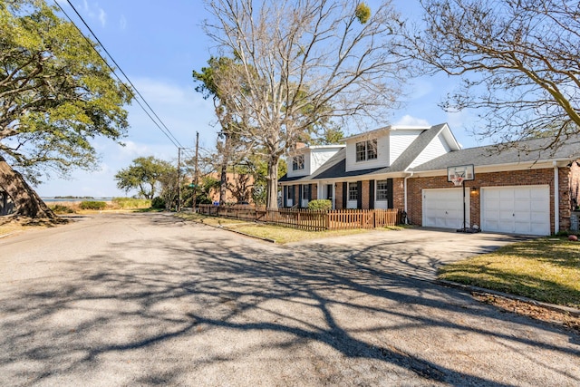 view of front of house with driveway, an attached garage, fence, a porch, and brick siding