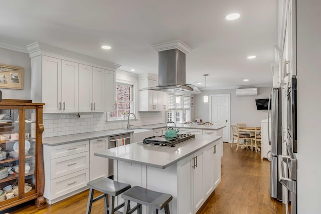 kitchen featuring a wall unit AC, a peninsula, a kitchen island, a kitchen bar, and island exhaust hood