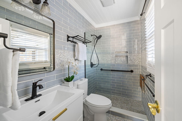 bathroom with tile walls, tiled shower, vanity, ornamental molding, and toilet