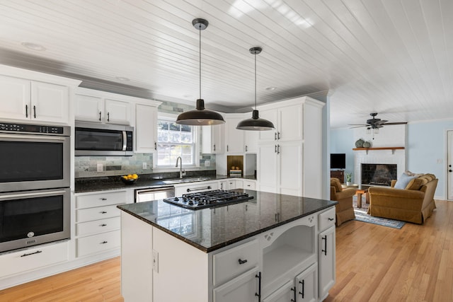 kitchen featuring sink, hanging light fixtures, stainless steel appliances, white cabinets, and a kitchen island