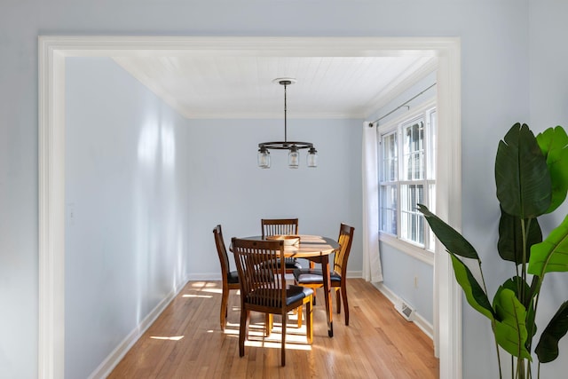 dining area featuring crown molding, a chandelier, and light hardwood / wood-style floors