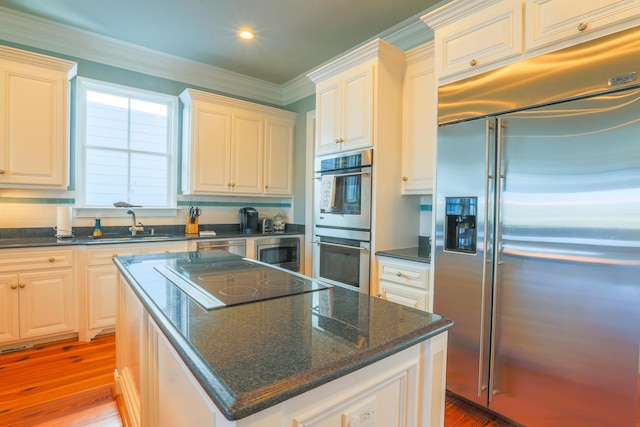 25 Ocean Point Dr, Isle Of Palms, SC 29451 - kitchen featuring built in appliances, a center island, light wood finished floors, a sink, and ornamental molding