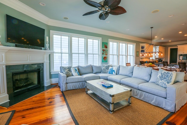 25 Ocean Point Dr, Isle Of Palms, SC 29451 - living room featuring a fireplace, light wood-style floors, ornamental molding, a ceiling fan, and a chandelier