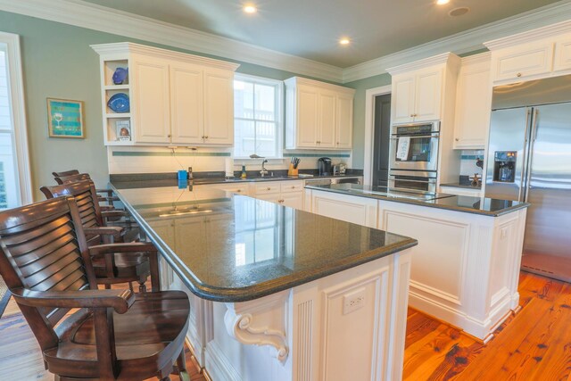 25 Ocean Point Dr, Isle Of Palms, SC 29451 - kitchen featuring a center island, stainless steel appliances, a peninsula, light wood-style flooring, and a breakfast bar