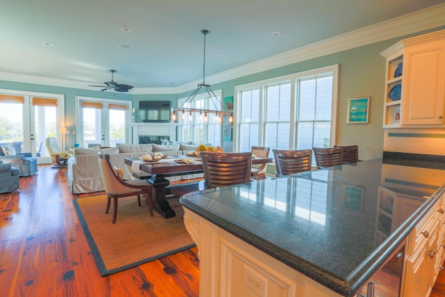 25 Ocean Point Dr, Isle Of Palms, SC 29451 - kitchen with ornamental molding, open floor plan, wood finished floors, decorative light fixtures, and french doors