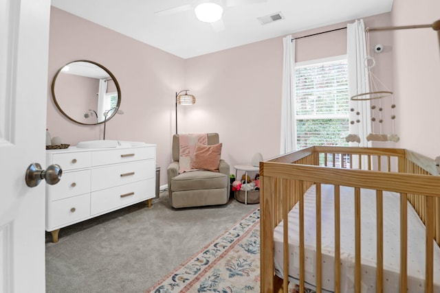 bedroom with ceiling fan, a nursery area, and carpet floors