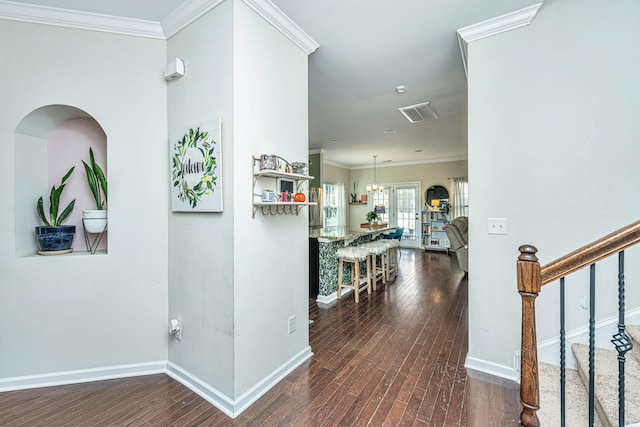 hallway with a chandelier, dark hardwood / wood-style flooring, and crown molding