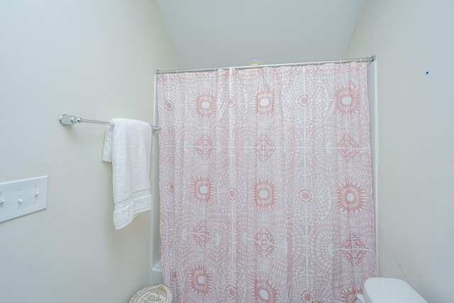 bathroom featuring toilet, lofted ceiling, and shower / tub combo with curtain