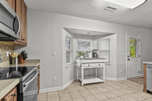kitchen featuring stainless steel appliances, light countertops, decorative backsplash, and brown cabinets