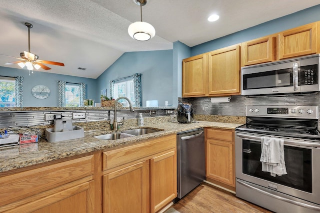 kitchen featuring light stone counters, sink, decorative backsplash, and appliances with stainless steel finishes