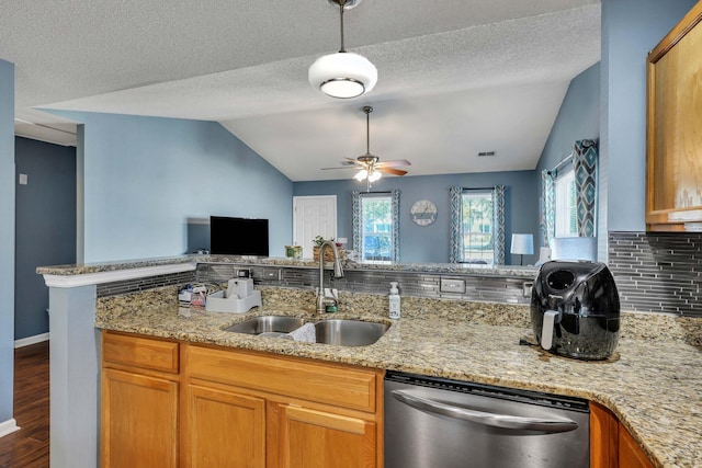 kitchen featuring lofted ceiling, sink, stainless steel dishwasher, light stone counters, and kitchen peninsula