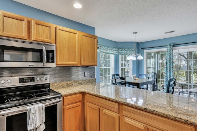 kitchen with tasteful backsplash, appliances with stainless steel finishes, decorative light fixtures, and light stone countertops