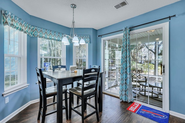 dining area featuring a textured ceiling, a notable chandelier, and dark hardwood / wood-style flooring