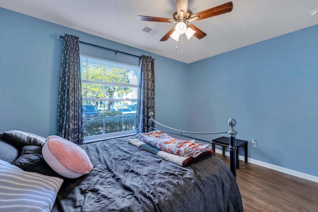 bedroom with hardwood / wood-style flooring, ceiling fan, and a textured ceiling