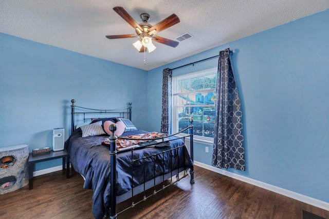 bedroom featuring ceiling fan, dark wood-type flooring, and a textured ceiling