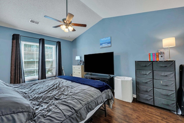 bedroom with ceiling fan, dark hardwood / wood-style floors, vaulted ceiling, and a textured ceiling