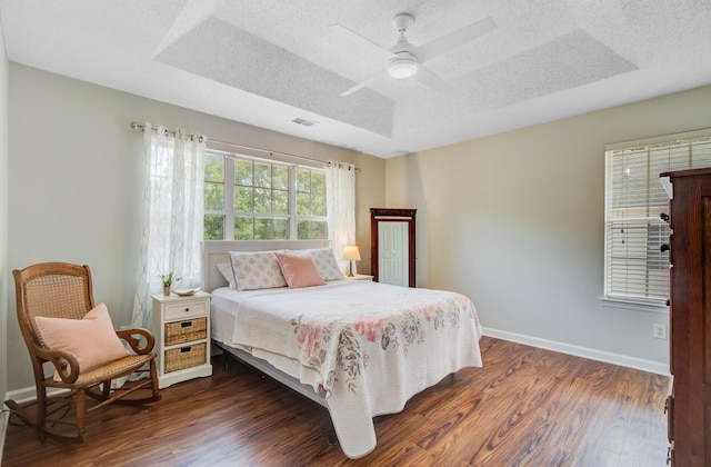 2404 Fulford Ct, Mount Pleasant, SC 29466 - bedroom featuring dark wood-style floors, a ceiling fan, a textured ceiling, and a tray ceiling