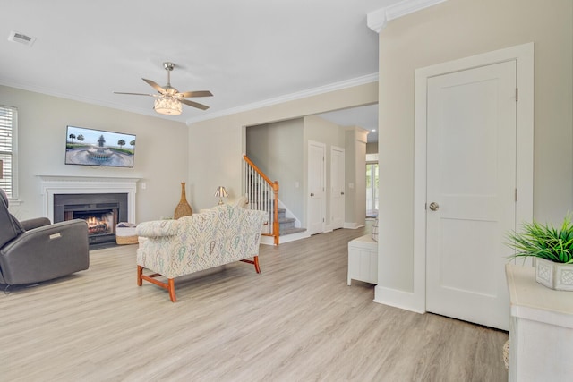 2404 Fulford Ct, Mount Pleasant, SC 29466 - living area featuring ornamental molding, light wood-type flooring, a fireplace with flush hearth, ceiling fan, and stairs