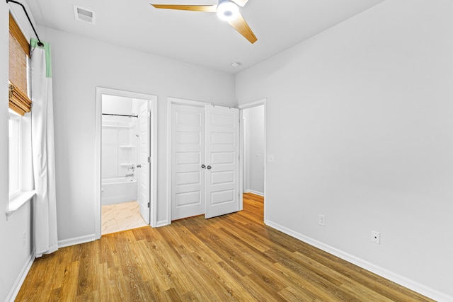 unfurnished bedroom with ensuite bath, ceiling fan, and hardwood / wood-style floors