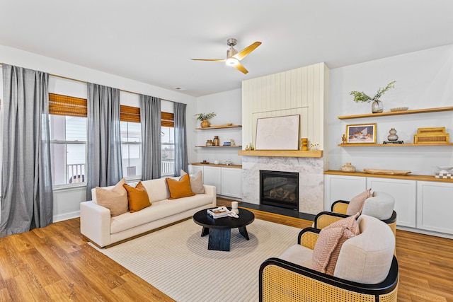 living room with light wood-type flooring, ceiling fan, and a fireplace