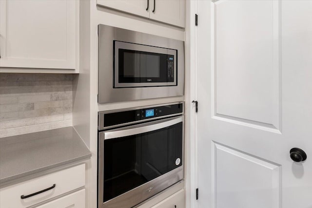 kitchen with backsplash, white cabinets, and stainless steel appliances