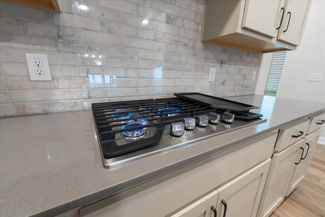 interior space with tasteful backsplash, light hardwood / wood-style floors, and stainless steel gas stovetop