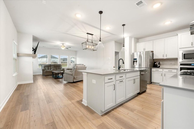 kitchen with white cabinets, pendant lighting, sink, and an island with sink